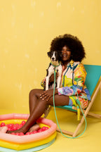 Woman sitting on a chair with a dog, both on a yellow background