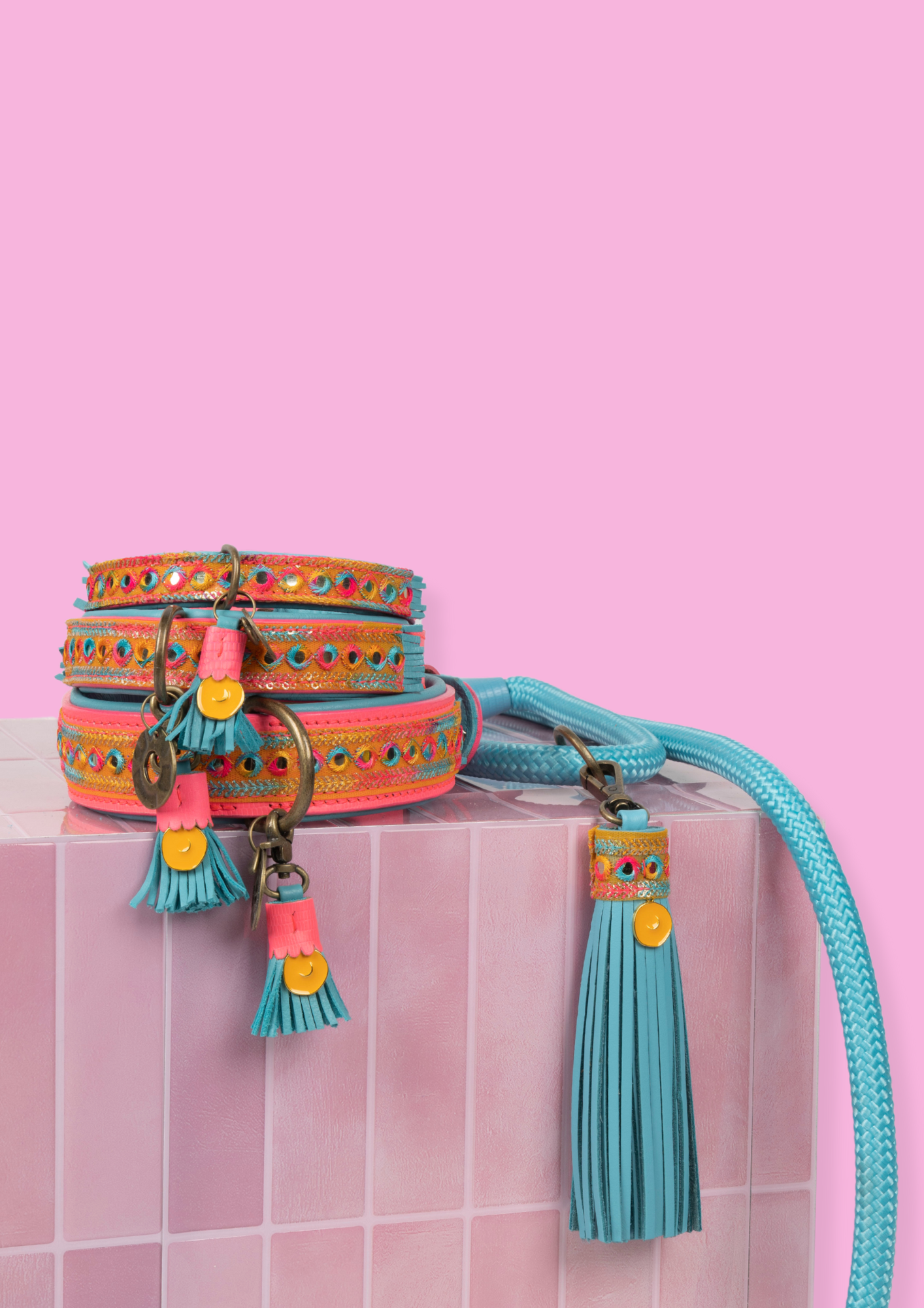 Colorful dog collar and leash set on a pink tiled surface with a pink background
